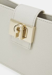 Hellgraue, strukturierte Lederhandtasche mit einem goldenen metallischen Verschluss. Verfügt über einen glatten Verschluss und gestickte Kanten. Kompakte rechteckige Form.