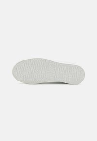 Fehér sneakerszól, mely texturált mintázattal rendelkezik; Calvin Klein logóval díszítve. Sima anyag, bordázott tapadással a stabilitás érdekében.