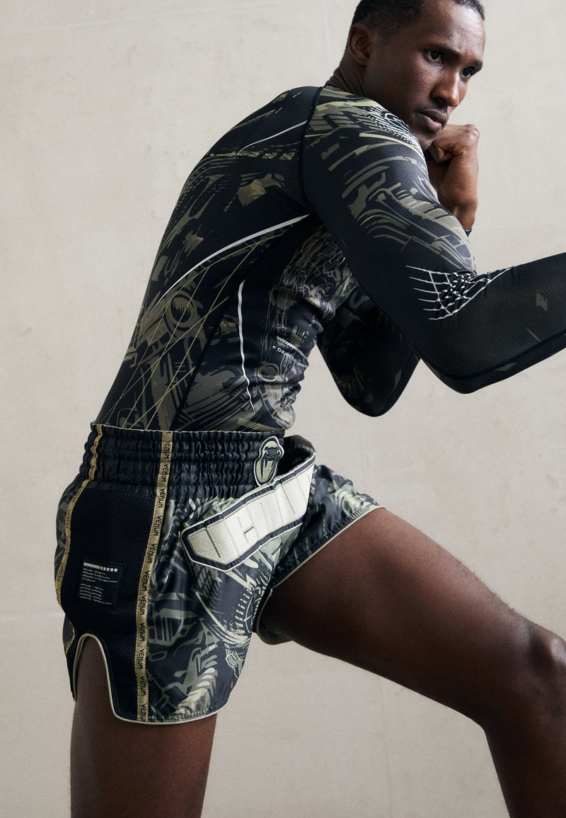 Black athletic shirt with intricate green patterns, paired with black and green shorts featuring a textured waistband and logo details.