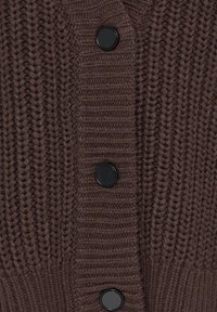 Gilet à grosses mailles marron foncé avec côtes verticales et trois gros boutons ronds noirs au centre.