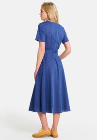 Sinine šambray kleit lühikeste varrukatega, rõhutatult vöökoht ja laienev seelikuosa. Kantud kollaste tossudega, tagaküljel on kinnituse detail.