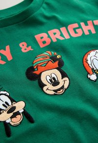 Zelené bavlnené tričko s výšivkou kreslených postavičiek: Mickey Mouse nosí slávnostný klobúk, vedľa neho sú zobrazení Goofy a Donald Duck.