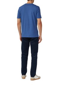 Niebieska bawełniana koszulka z krótkim rękawem i okrągłym dekoltem, w połączeniu z granatowymi spodniami i białymi trampkami. Prosty, elegancki design.