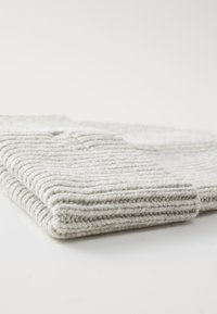 Knitted blanket in light gray with a ribbed texture, featuring folded edges and a thick, cozy appearance.