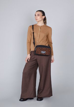 Cardigan marrone con bottoni dorati, pantaloni larghi marroni e una borsa a tracolla nera con un motivo a spina di pesce arancione e hardware argentato.