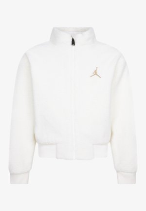 Veste en polaire blanche zippée avec col haut, poignets et bas élastiques, comportant un petit logo Jumpman doré sur la poitrine gauche.