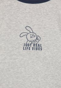 Sivý bavlnený tričko s námořníckym modrým okrúhlym výstrihom. Potlač obsahuje postavičku zajaca a text "LEN SKUTKOVÉ ŽIVOTNÉ VIBRÁCIE" pod ním.