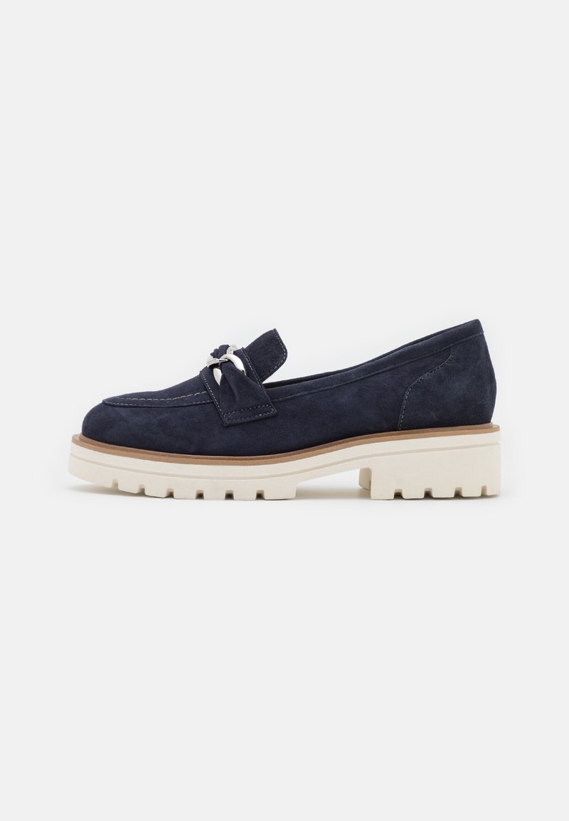 Des mocassins en daim bleu marine avec une semelle blanche basse et épaisse ainsi qu'un nœud décoratif. Le design est élégant avec des détails de couture contrastants.