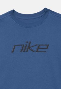 Niebieska koszulka z okrągłym dekoltem z logo "riike" nadrukowanym na piersi czarnymi i niebieskimi wzorzystymi literami.