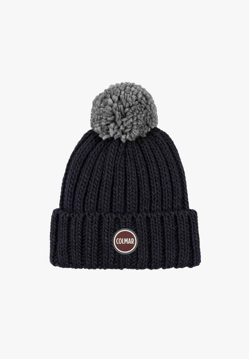 Neulepipo tummansinisellä värillä ja harmaalla pom-pomilla päällä. Siinä on ribbikuviointi ja pyöreä punasilverinen logotarra edessä.