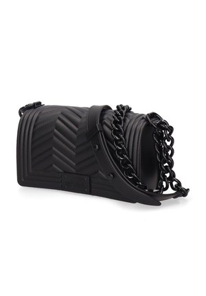 Zwarte doorgestikte leren schoudertas met chevronpatroon en een brede kettingriem, liggend op een wit oppervlak.