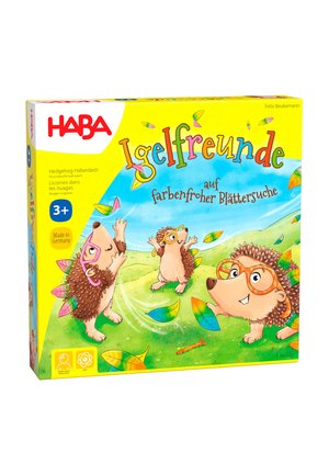 Colorful board game box with three playful hedgehogs wearing glasses, catching colorful leaves on a grassy hill under a blue sky.