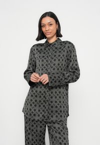 Saténová košeľa s monochromatickým geometrickým vzorom zaoblených tvarov, dlhými rukávmi a klasickým golierom.