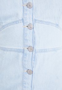 Ljusblå denimklänning med knapplås framtill och silverfärgade knappar, sömdekoration och en strukturerad passform. Enhetlig textur genomgående.