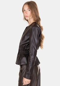 Giacca in ecopelle nera con vita aderente, design a baschina e maniche lunghe. Texture liscia e scollo rotondo minimalista.