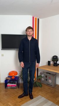 Μπλέ ζακέτα με φερμουάρ και γιακά, φορεμένη πάνω από σκούρα τζιν και καφέ παπούτσια. Η ζακέτα διαθέτει λεία υφή και μινιμαλιστικό σχέδιο.