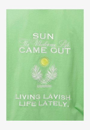Roheline puuvillane t-särk, millel on valge brodeeritud tekst ja päikese graafika koos palmi lehtede ja laine motiividega. Pehme tekstuur, lõdva istuvusega.