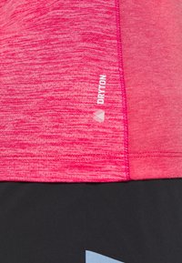 Top sportivo rosa con motivo strutturato screziato e logo bianco "DRAYTON" sul lato, abbinato a pantaloncini neri con accento blu.