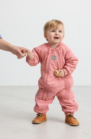 Rosa polstret snowsuit med quiltet design, med elastiske mansjetter og en logo-patch. Barnet holder en trekloss og har på seg brune støvler.
