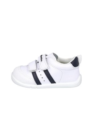 Zapatilla blanca para niño pequeño con dos rayas negras, tiras de velcro, puntera reforzada y lengüeta en el talón azul oscuro sobre fondo blanco.