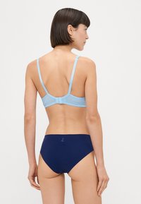Sutien bleu deschis cu textură canelată, bretele ajustabile și închidere cu cârlig; asortat cu chiloți de baie solidi de culoare bleumarin.