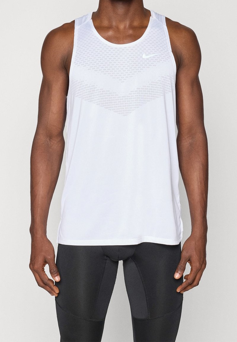 Valkoinen Nike-hihaton paita, jossa on teksturoidusta chevron-muotoilusta tehty kuvio edessä. Kevyt kangas, ilman hihoja, ja pyöreä pääntie.