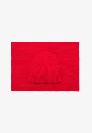 Berretto di lana rosso a maglia sopra una sciarpa piatta coordinata. Entrambi i pezzi presentano una texture a coste e sono di un uniforme colore rosso brillante.