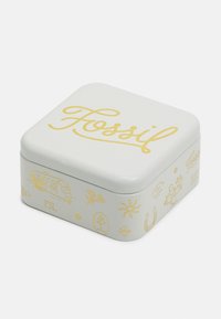 Boîte en métal carrée avec un extérieur blanc, présentant le texte "Fossil" en jaune et un art linéaire décoratif incluant une caravane et des fleurs.