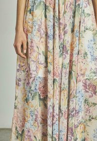 Florales Maxikleid aus leichtem Stoff mit einem mehrfarbigen Muster aus Rosen und Flieder in Pastellfarben auf hellem Hintergrund.