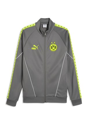 Graue Sportjacke mit Reißverschluss mit gelbem Puma-Logo, Text "KING" und BVB 09 Fußballvereinswappen, mit gelben Streifen an den Ärmeln.
