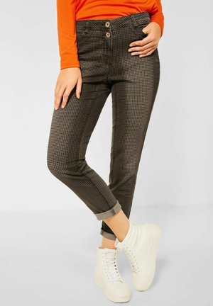 Dark green patterned trousers with a checkered design, featuring a high waist, two front buttons, rolled cuffs, and slim fit. Paired with white high-top sneakers.
