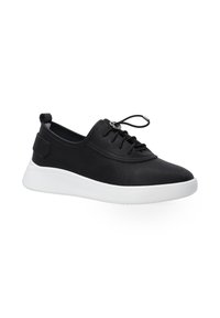 Schwarze Slip-On-Sneaker mit strukturiertem Obermaterial und weißer Sohle, ausgestattet mit elastischen Schnürsenkeln und einer kleinen Fersenschlaufe für einfaches Anziehen.