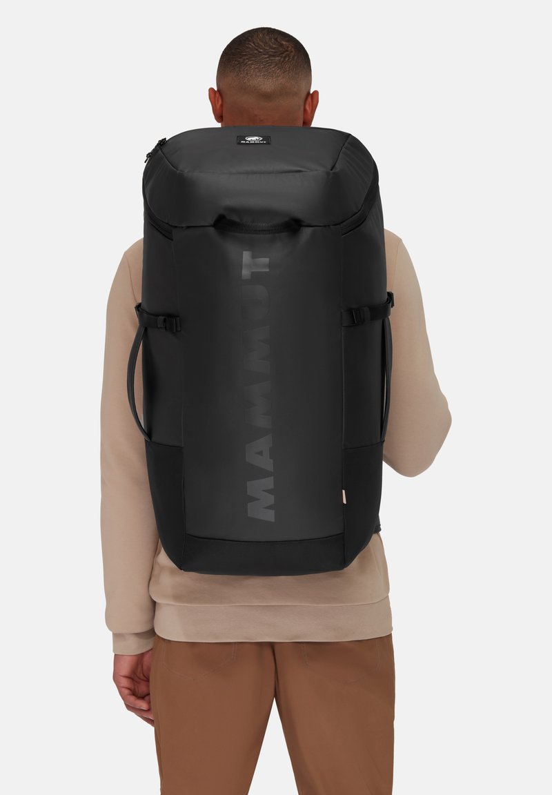 Black backpack with matte finish, sturdy design, large main compartment, visible logo, adjustable straps, and side pockets for storage.