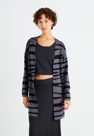 Gray and black striped cardigan with an open front, long sleeves, and soft knit texture, worn over a black cropped top and ribbed skirt.