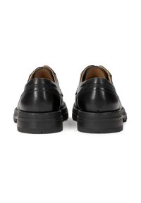 Zapatos de cuero negro con una textura suave, tacón redondeado y forro en contraste en color marrón claro. Presentan costuras sutiles a lo largo de la parte trasera.