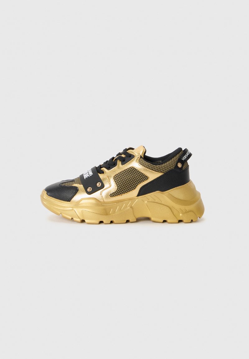 Sorte og gyldne sneakers med en mesh-overdel, tyk sål og dekorative detaljer. Har et iøjnefaldende logo-patch på snørebåndsområdet.