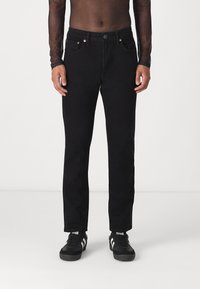 Jeans de ganga pretos com corte reto, cinco bolsos, bot�ão de metal e costura em contraste. Combinados com ténis pretos.