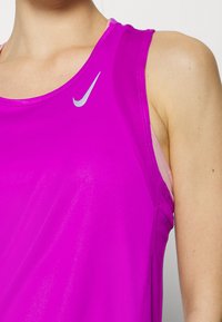 Tætsiddende tanktop i klar pink med rund halsudskæring, skulderstropper og en sølvfarvet Nike-logo foran. Glat, letvægtsstof.
