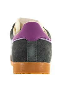 Sneaker in suede grigio con un inserto in pelle viola sul tallone, una striscia bianca di accento e suola in gomma; presenta dettagli di cucitura e una parte superiore testurizzata.