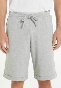 Pantalones cortos de algodón grises con cintura elástica, cordón ajustable y dobladillos enrollados. La tela tiene una textura suave y lisa.