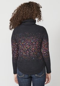 Tmavý svetr s vysokým límcem, na zadní straně s vícerozměrným, vzorovaným pleteným designem. Hladká textura, žebrované manžety a lem.