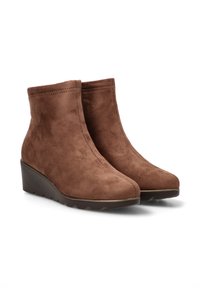 Botas de tobillo de ante marrón con tacón en cuña, que presentan una superficie suave y texturizada y una silueta elegante. Detalle de costura mínima.