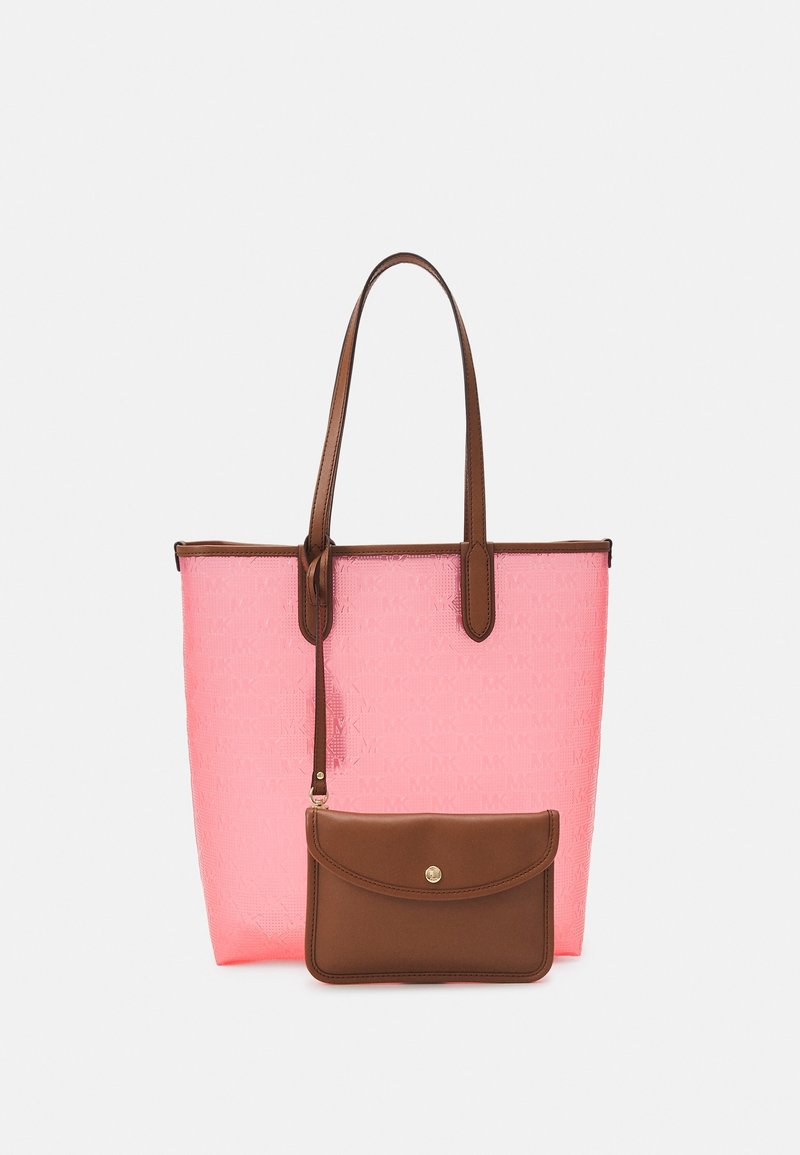 Sac fourre-tout rose avec de longues anses marron et une petite pochette marron attachée avec une fermeture à bouton doré sur fond uni.