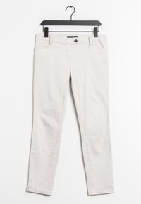 Jean en coton beige clair sur un cintre noir. Doté d'une fermeture à bouton, de cinq poches et d'une coupe slim avec des ourlets cousus.