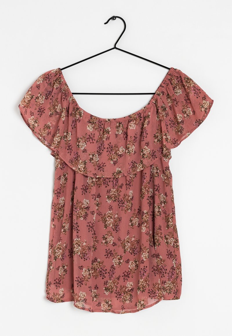Top floreale off-shoulder in tessuto rosa con scollatura arricciata. Presenta un delicato motivo di fiori e una texture sottile. Appeso a un gancio nero.