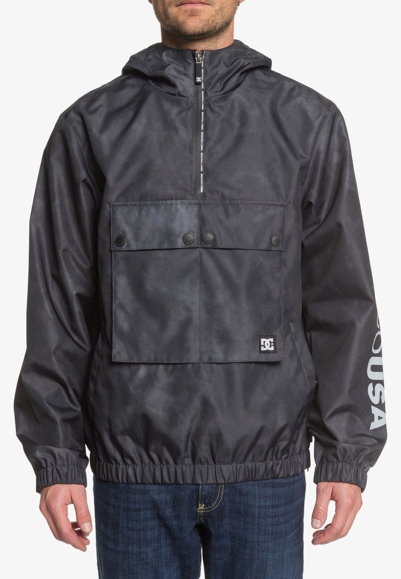 Black hooded pullover jacket in lightweight, water-resistant material. Features a zippered front, large chest pocket, and elasticized hem.