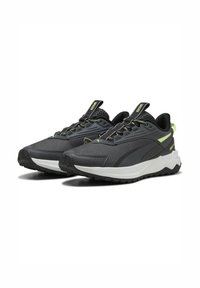 Baskets de sport avec une tige en mesh noir, des accents verts et une semelle grise texturée. Elles comportent un col rembourré et un système de laçage sécurisée.