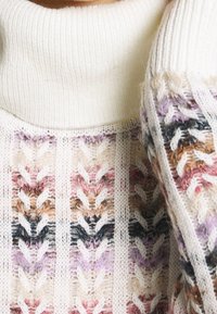 Strickpullover mit einem hohen, weißen Rippkragen. Der Körper zeigt ein mehrfarbiges, strukturiertes Muster in Rosa-, Lila- und Brauntönen.