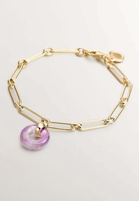 Pulsera de cadena de oro con grandes eslabones en forma de clip de papel y un colgante geométrico morado. Textura suave y acabado brillante en el metal y la piedra.