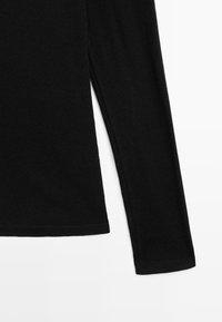 Schwarzes Langarmshirt mit gerippter Textur, Rundhalsausschnitt und gerade geschnittenem Saum. Der Stoff wirkt weich und elastisch.